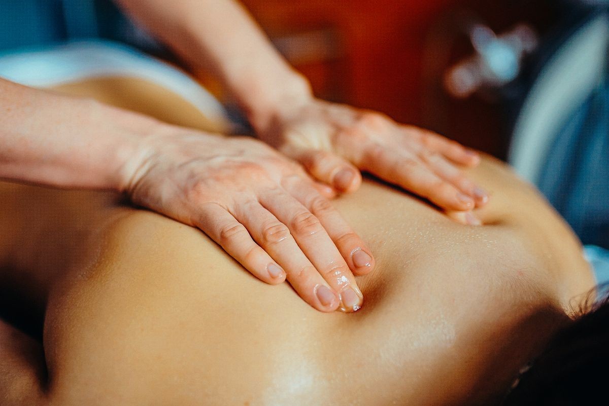 Woman having spa body massage treatment in the spa salon. Toned image. concept of healthcare and female beauty. The masseuse makes a back massage with a massage oil. hands view